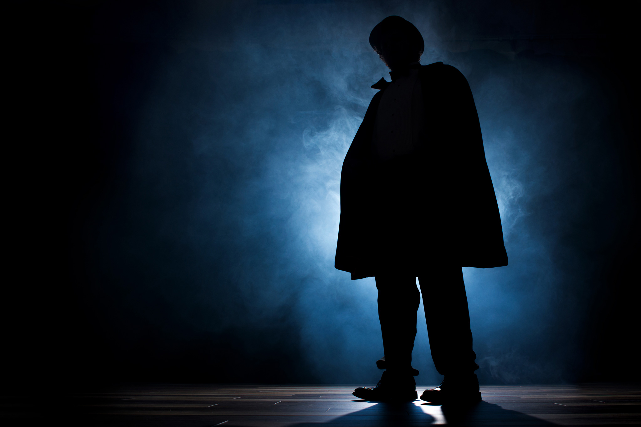 Silhouetted figure on stage, backlit with fog