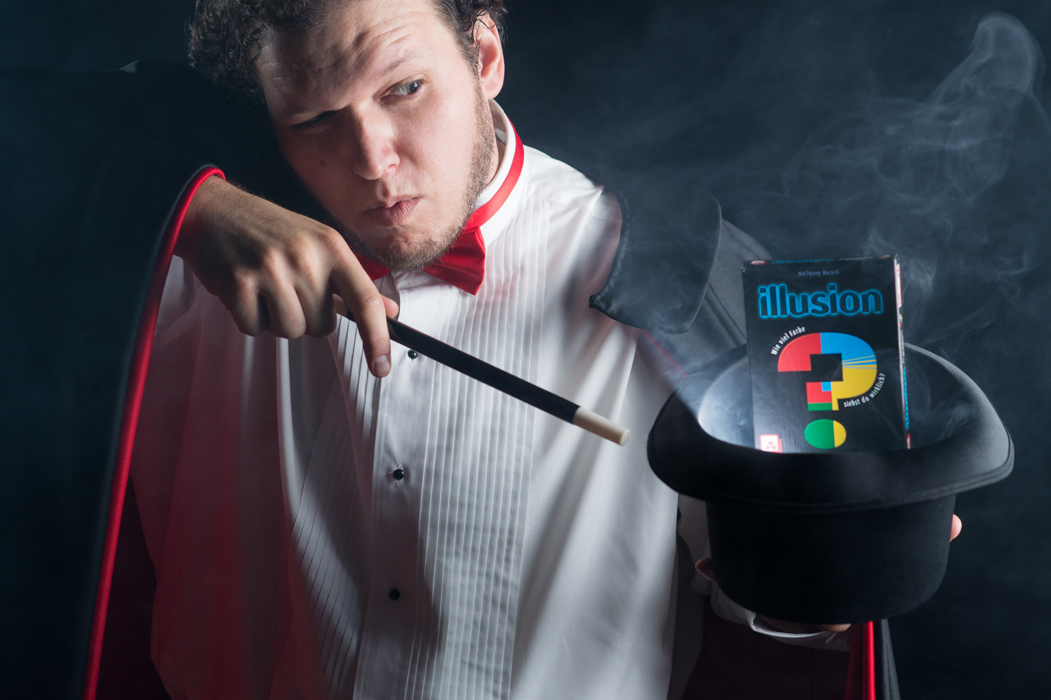 A magician makes the box for the game Illusion float out of a hat